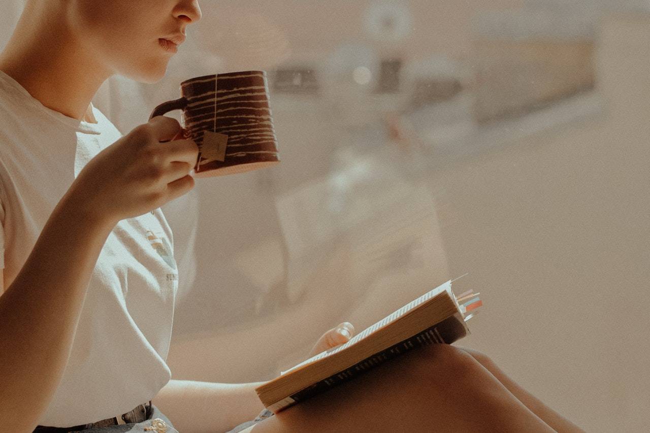 a woman drinking tea while reading a book - darren yaw wife website